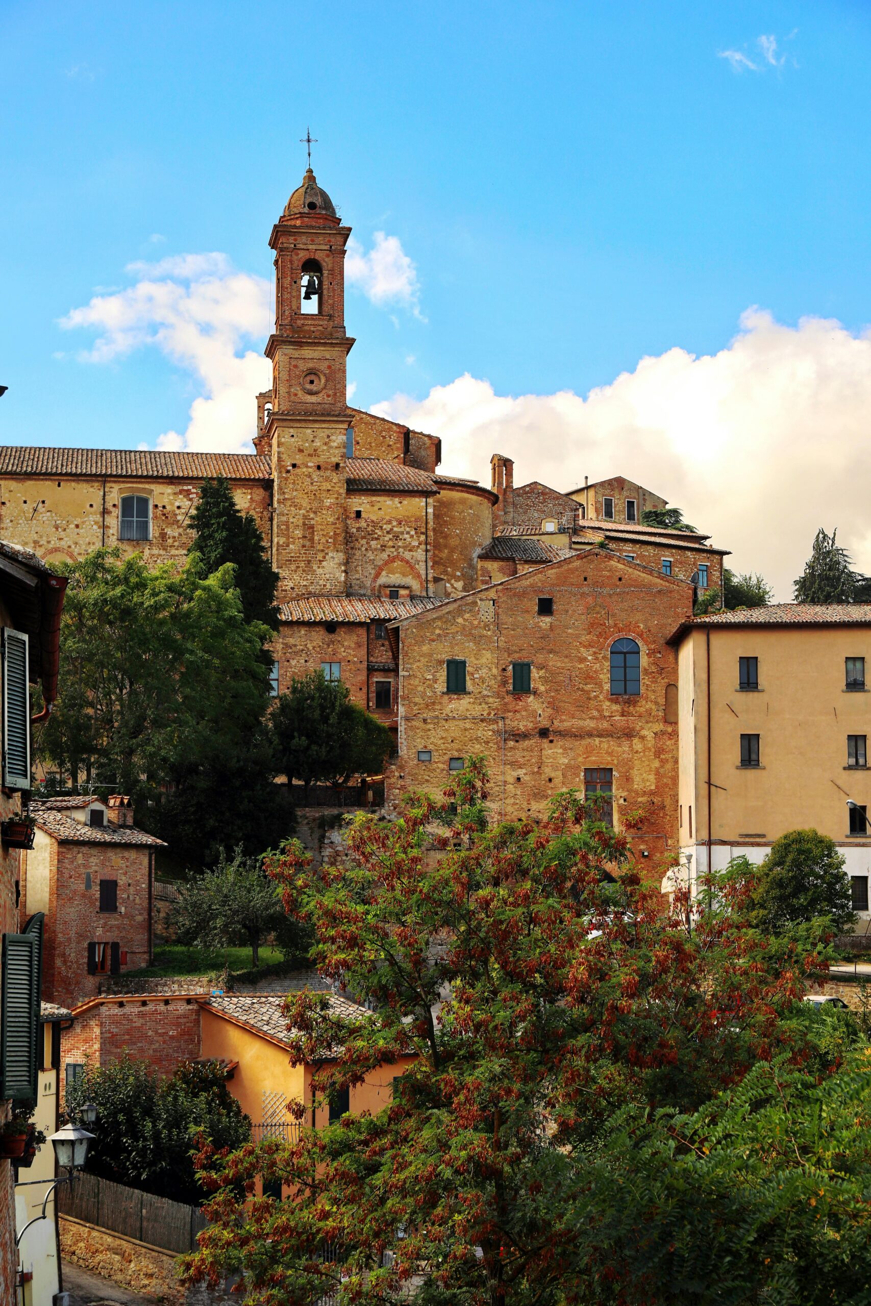 Explore the charming architecture of Montepulciano, Tuscany, with timeless stone buildings and lush greenery.