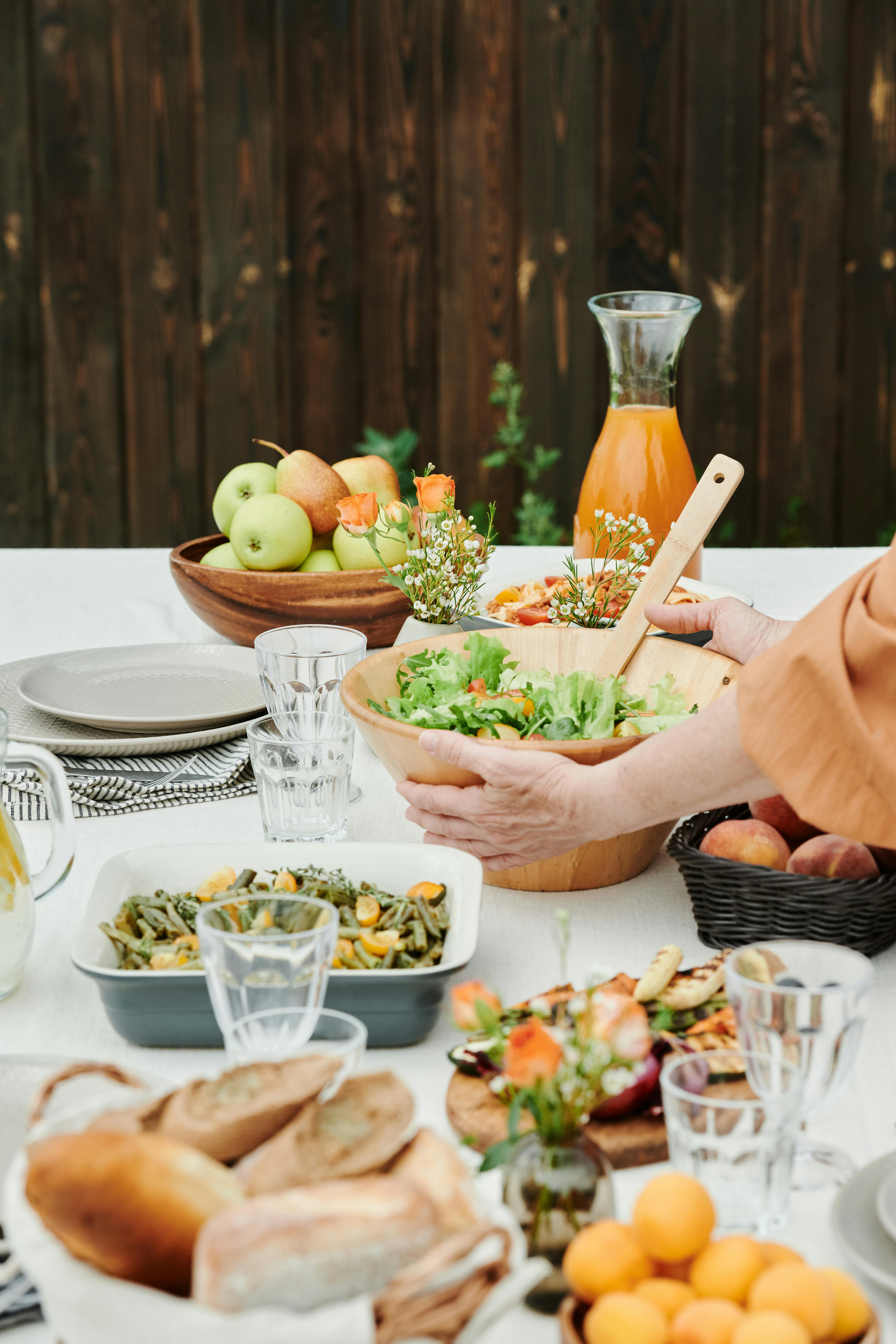 Vibrant outdoor dining table setting with a variety of fresh foods and drinks, ideal for summer gatherings.
