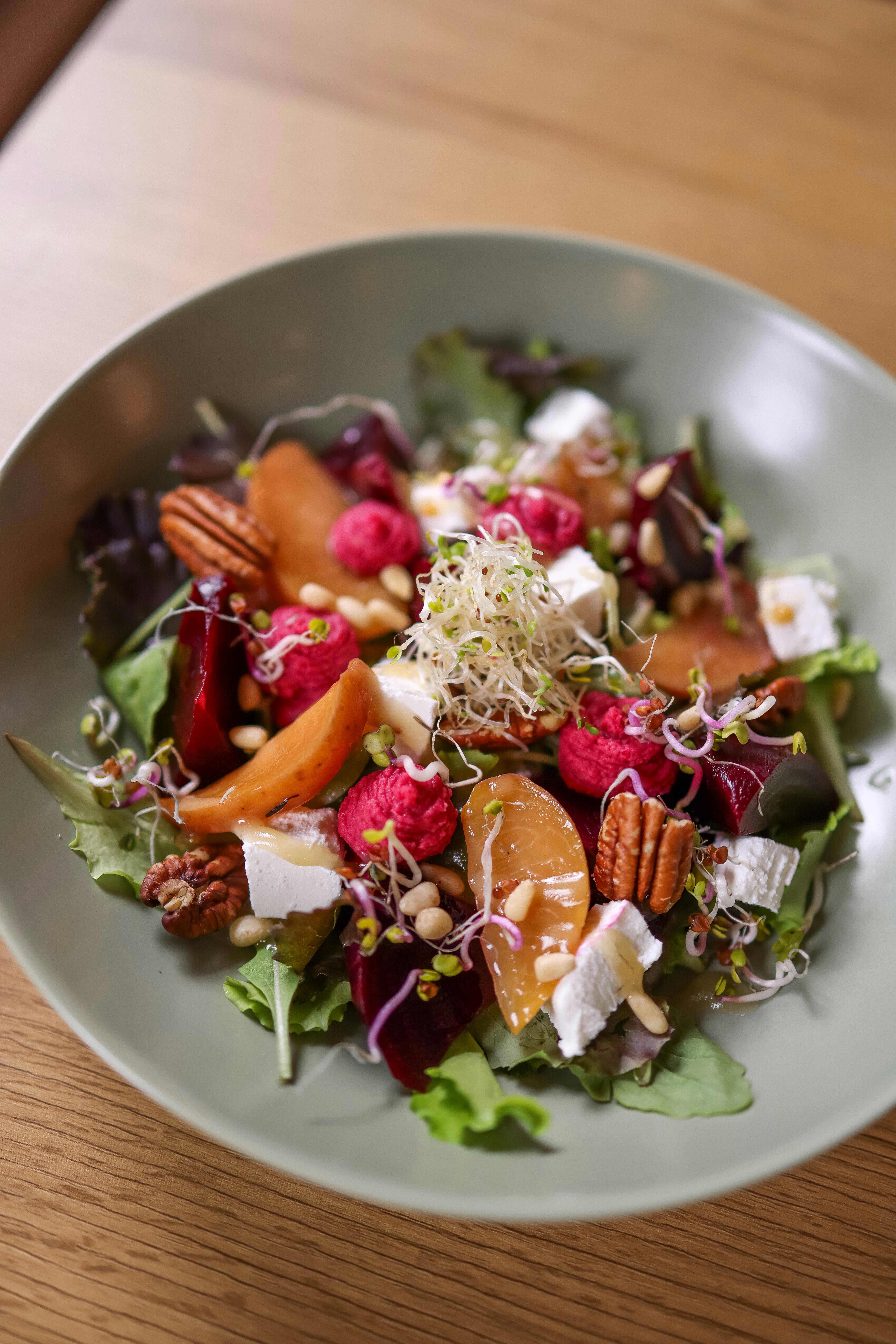 A delicious and colorful beet and goat cheese salad topped with pecans and sprouts.