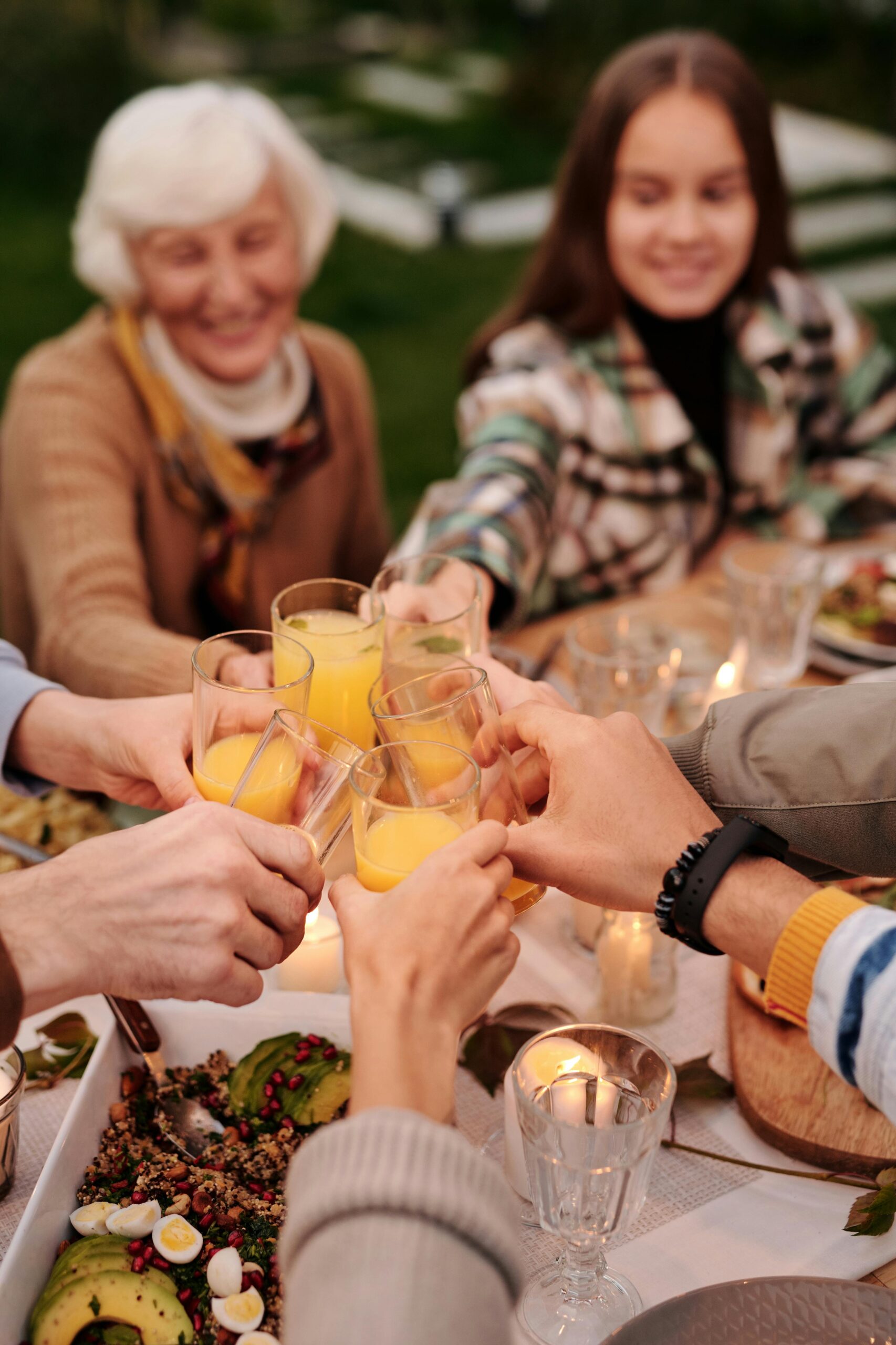 Faceless group of people enjoying family reunion and toasting with orange juice spending time in garden