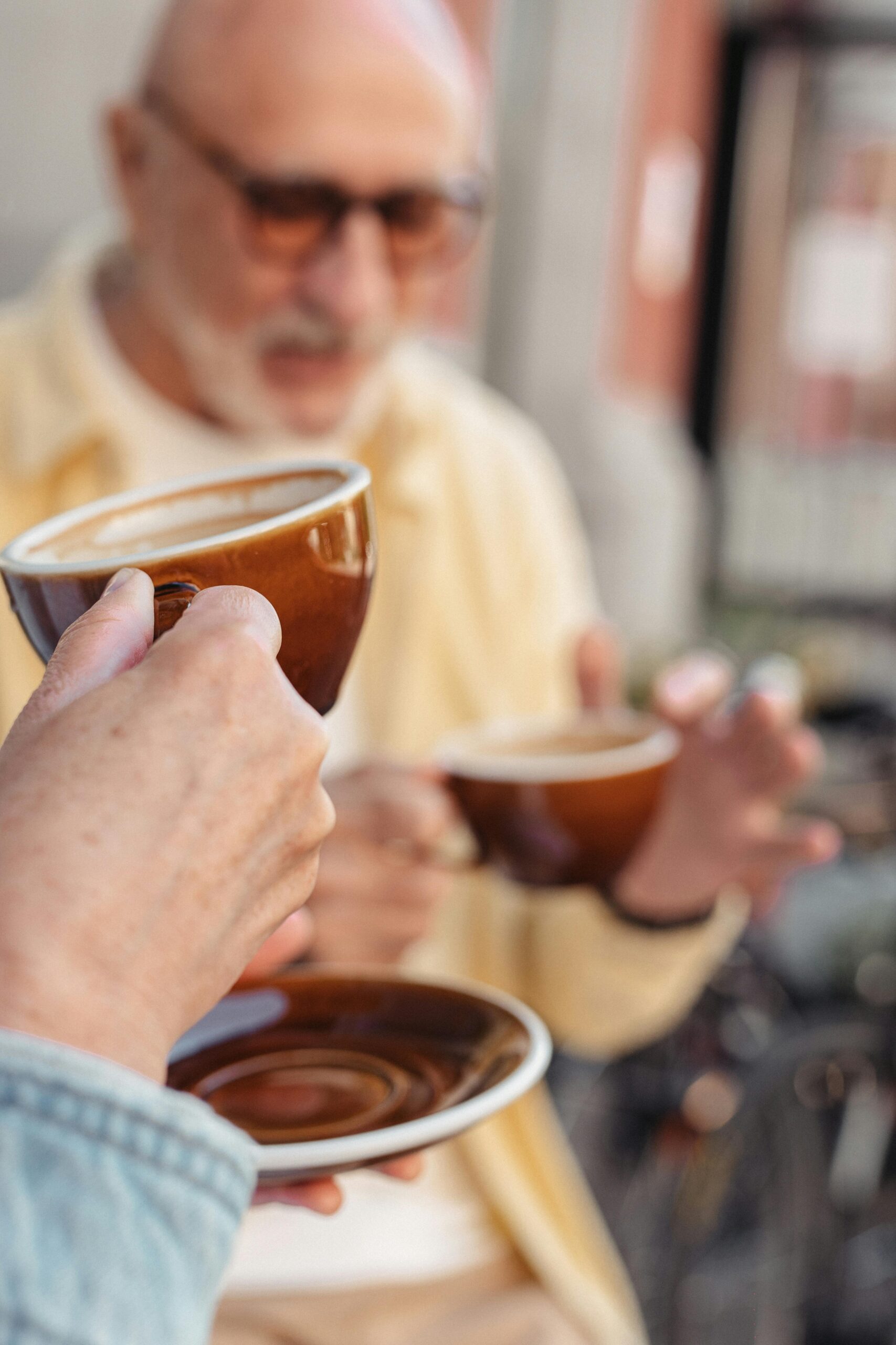 Writing Escape Tuscany Two senior adults savor coffee, holding mugs, in a warm social setting.