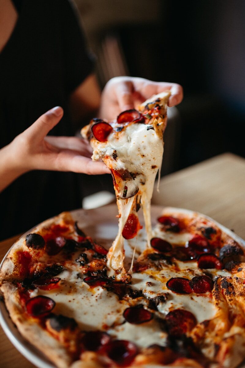 Writing Escape Tuscany a person takes a slice of pizza