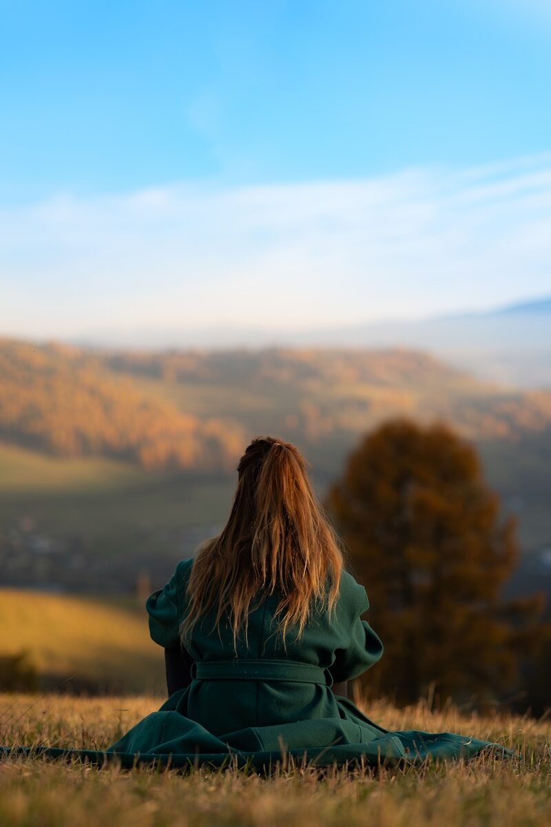 Writing Escape Tuscany A woman in a green coat sitting on a hill