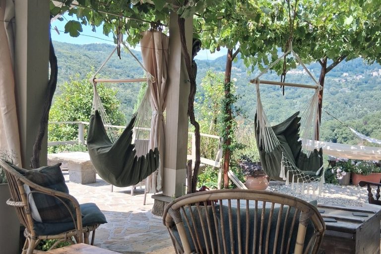 Outdoor pergola with hanging hammock chairs overlooking the Tuscan hills, seating area at Breathe Tuscany wellness retreat