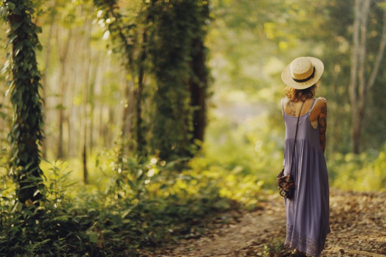 Woman walking along a dappled forest trail during a wellness retreat in Tuscany