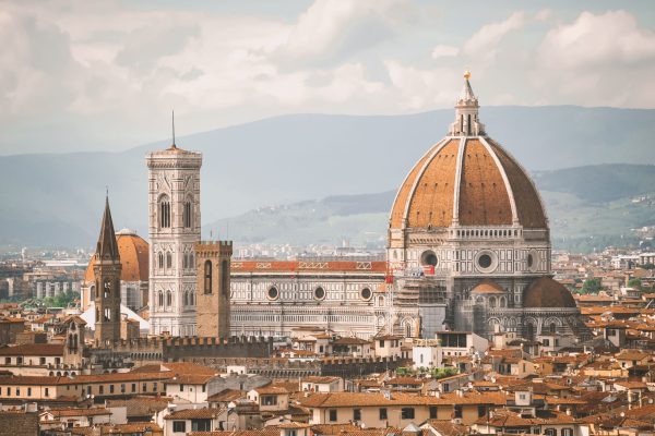 Florence skyline with the terracotta dome of the Duomo, Giotto's bell tower, and red-tiled rooftops with hills in the distance