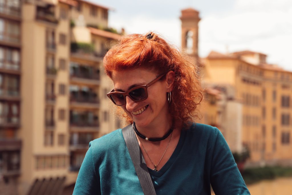Woman with red hair smiling outdoors in Florence