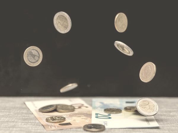 Euro coins falling onto banknotes on a table, illustrating tipping in Italy