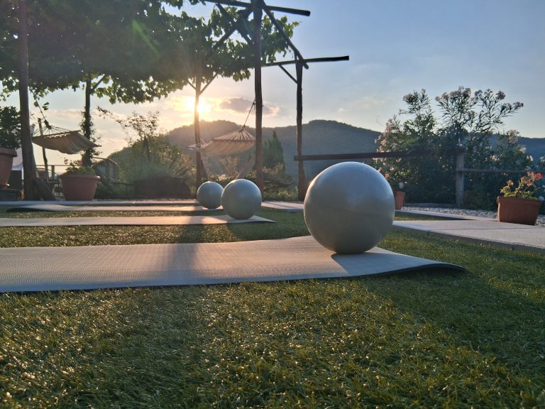 Yoga mats and exercise balls set up on the lawn at sunset during a women's wellness retreat in Tuscany, Italy